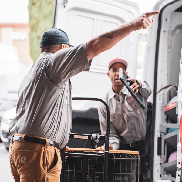 two technicians moving HVAC unit